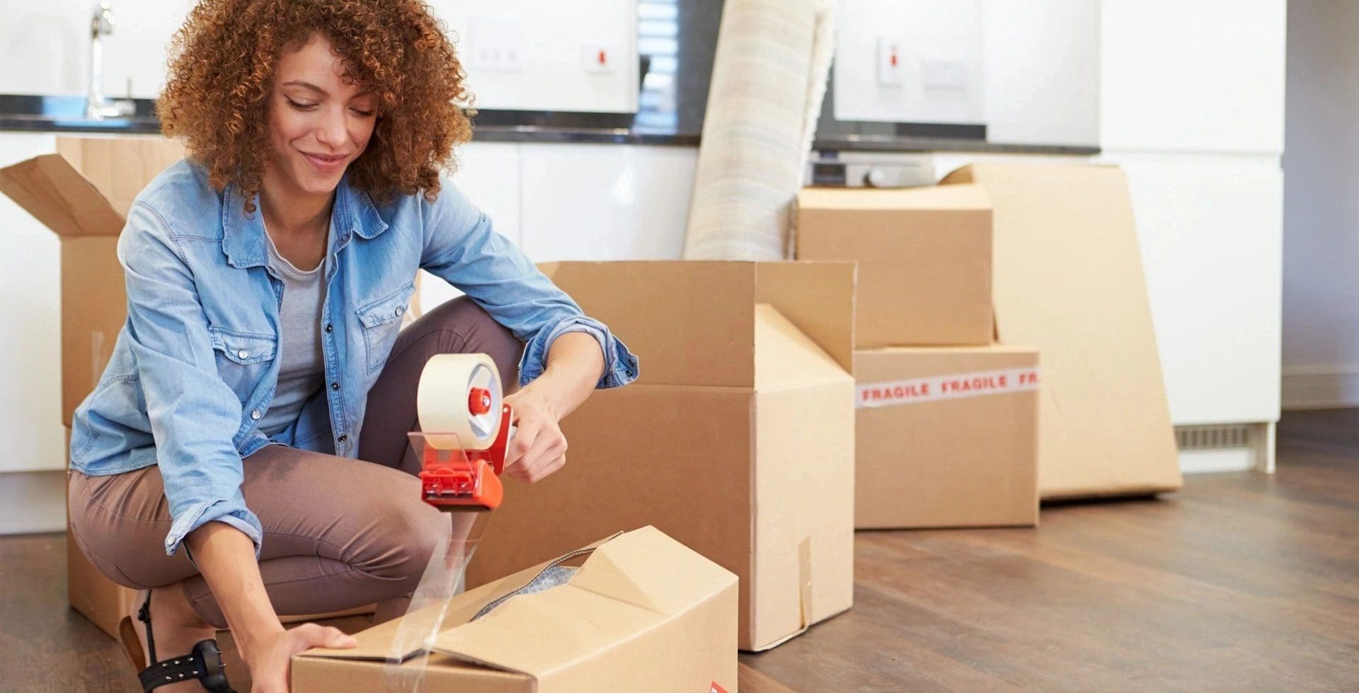 A woman is taping boxes with tape.